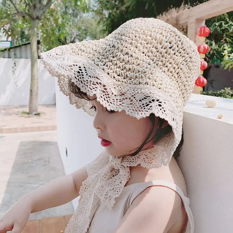 Close-up of a girls' straw sun hat featuring intricate lace detail, perfect for summer sun protection