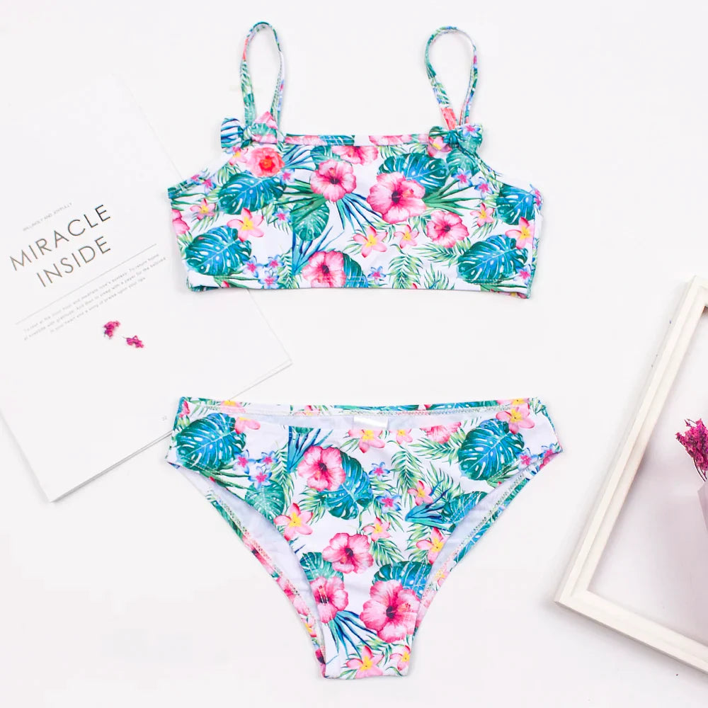 Set of three girls' print bikini options: polka dot, flamingo, and floral with bow details