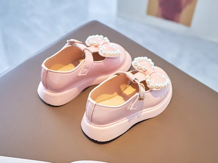 Pink girls shoes with a delicate bow-knot and pearl accents, suitable for young children.
