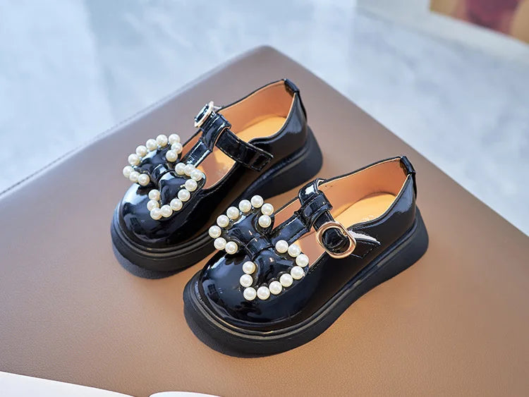 Fashionable girls pink shoes, adorned with a pretty bow-knot and shimmering pearls, toddler size.
