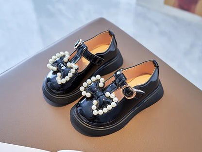 Fashionable girls pink shoes, adorned with a pretty bow-knot and shimmering pearls, toddler size.