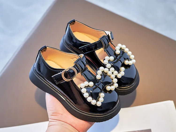 Overhead view of pink girls shoes, princess flats style, with a prominent bow-knot and pearls.