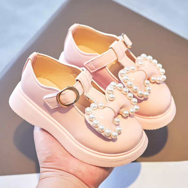 Toddler girls pink ballet flats with a shiny bow-knot and pearl details, ideal for special occasions.