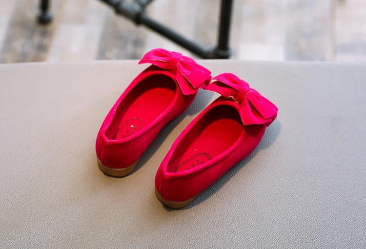 Young girl's feet wearing blue bowtie slip-on sandals, enjoying summer outdoor activities