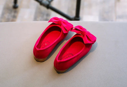 Young girl's feet wearing blue bowtie slip-on sandals, enjoying summer outdoor activities