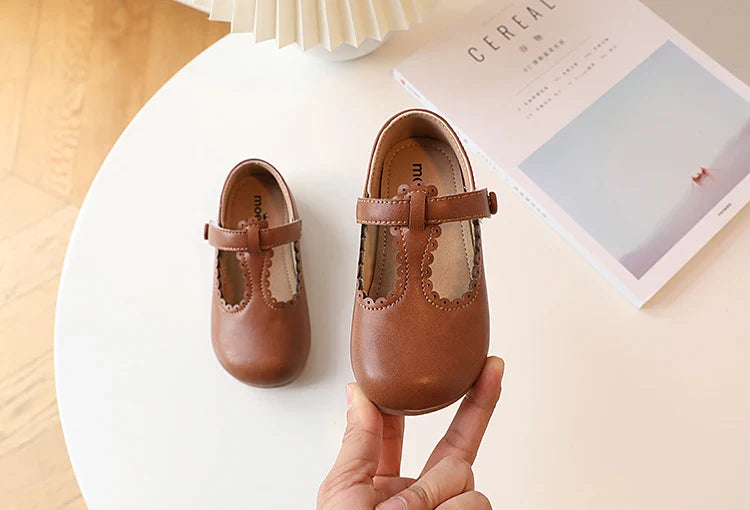 Detailed shot of the retro stitching on girls' T-strap flats, vintage princess style, PU leather