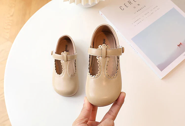 Overhead view of girls' white T-strap flats, vintage princess shoes, classic and comfortable