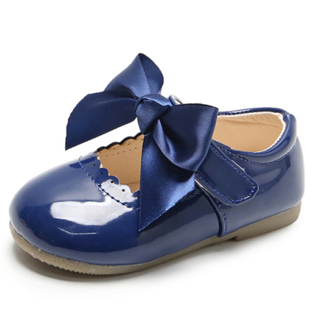 Side view of a girl's blue lace shoe with an oversized ribbon bow, stylish baby princess party footwear