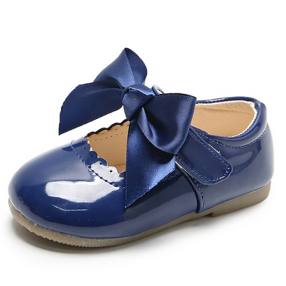 Side view of a girl's blue lace shoe with an oversized ribbon bow, stylish baby princess party footwear