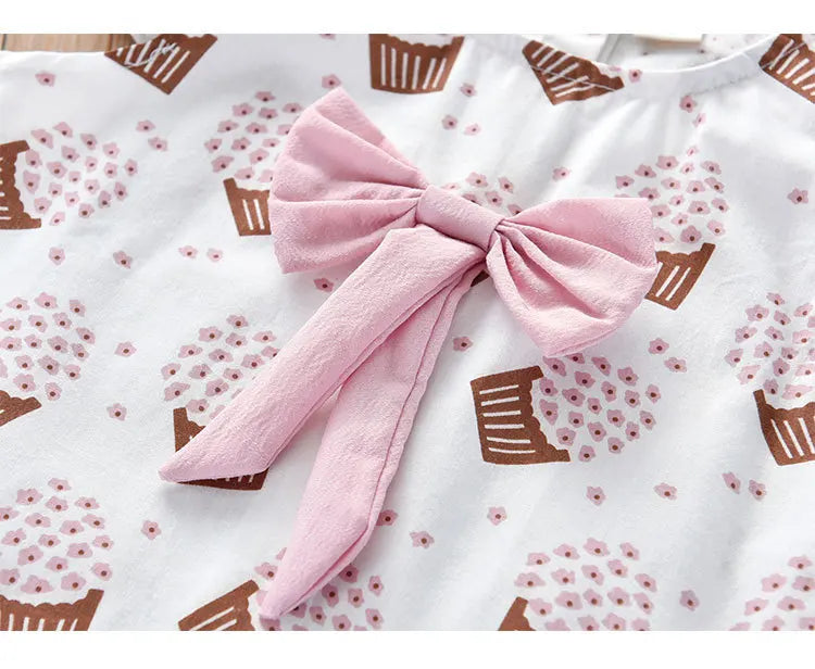 A close-up of the ice cream print and bow on girls' sleeveless pink summer clothing
