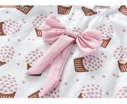 A close-up of the ice cream print and bow on girls' sleeveless pink summer clothing