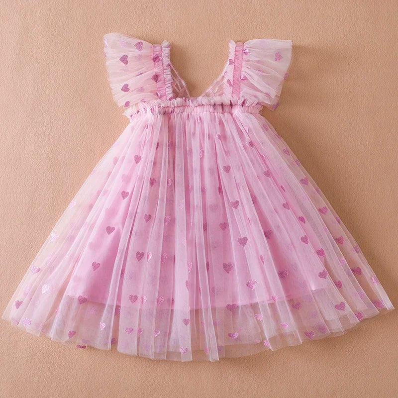 Little girl twirling in a back bow wing tulle party dress, showcasing its full, flowing skirt.
