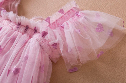 A vibrant pink girls' tulle dress with back bow and wing embellishments, great for parties.