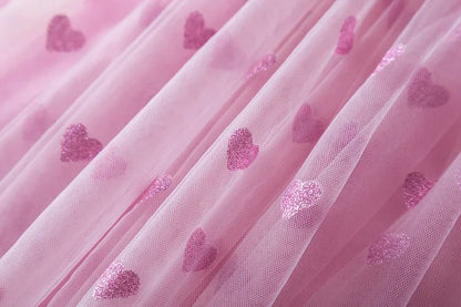 Happy girl wearing a pink back bow wing tulle party dress, ready for her birthday celebration.