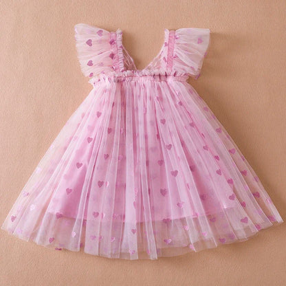 Toddler girl in a white wing tulle party dress with large back bow, ideal for summer celebrations.