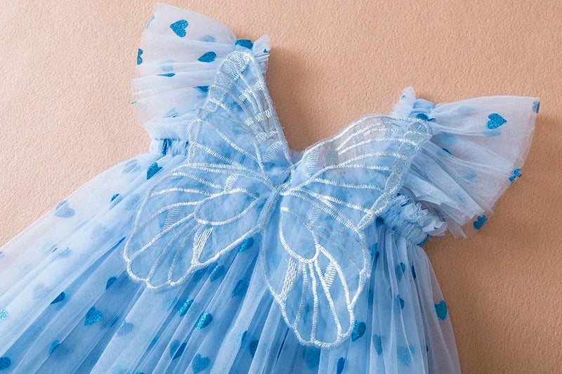 Zoomed-in shot of the soft tulle fabric and wing detail on a girls' back bow party dress.