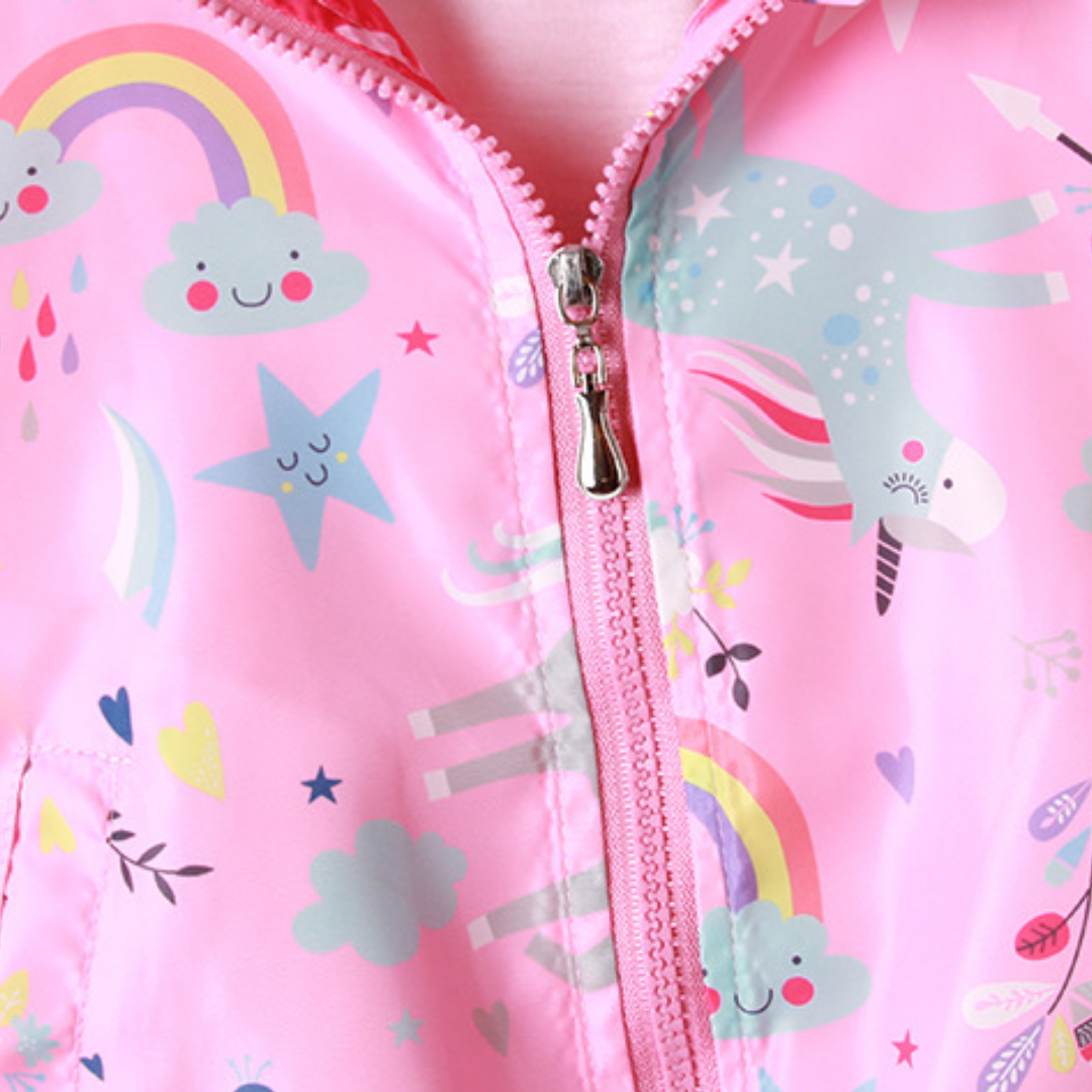 Toddler girl smiling in a colorful unicorn windbreaker jacket, perfect for outdoor playwear