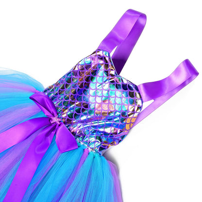 Toddler girl in a sparkling mermaid princess party dress, iridescent scales on top, with a cute fin-like hem.
