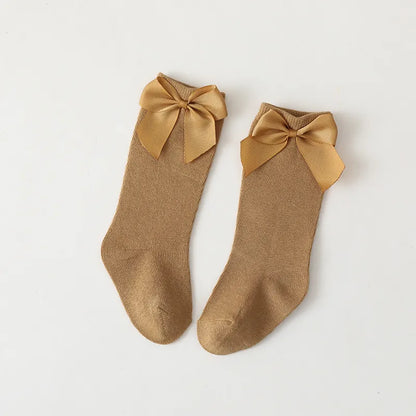 Packaged set of three cotton knee-high bow socks for girls; essential toddler accessories