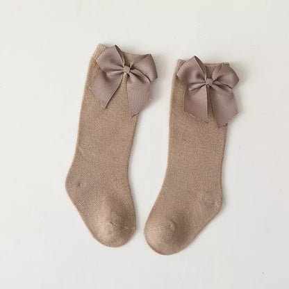 Side view of a girl's leg with white cotton knee-high bow sock; cute summer fashion