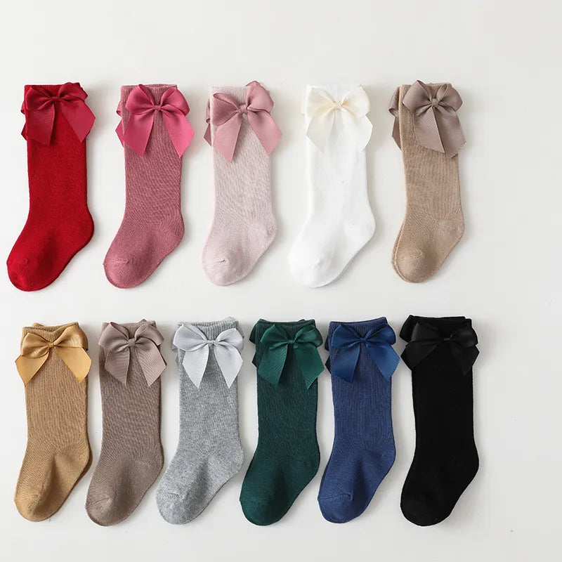 Close-up of pink cotton knee-high socks with delicate bow; perfect for baby accessories