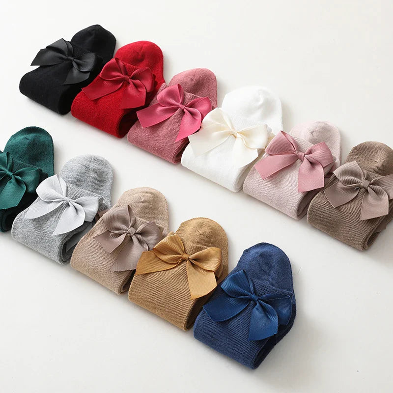 Stacked pairs of cotton knee-high bow socks for girls; organized baby accessories