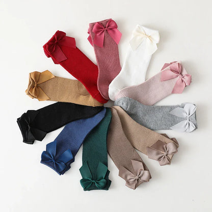 Two pairs of girls' cotton knee-high socks, white and pink, with bows; children's apparel