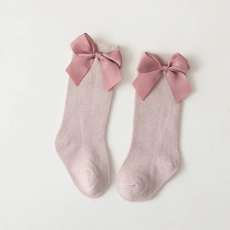 Little girl's legs with cute pink cotton knee-high bow socks; baby accessories