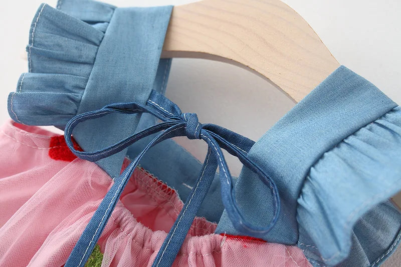 Back view of a lovely white girls' dress, showcasing strawberry embroidery and the bow detail.