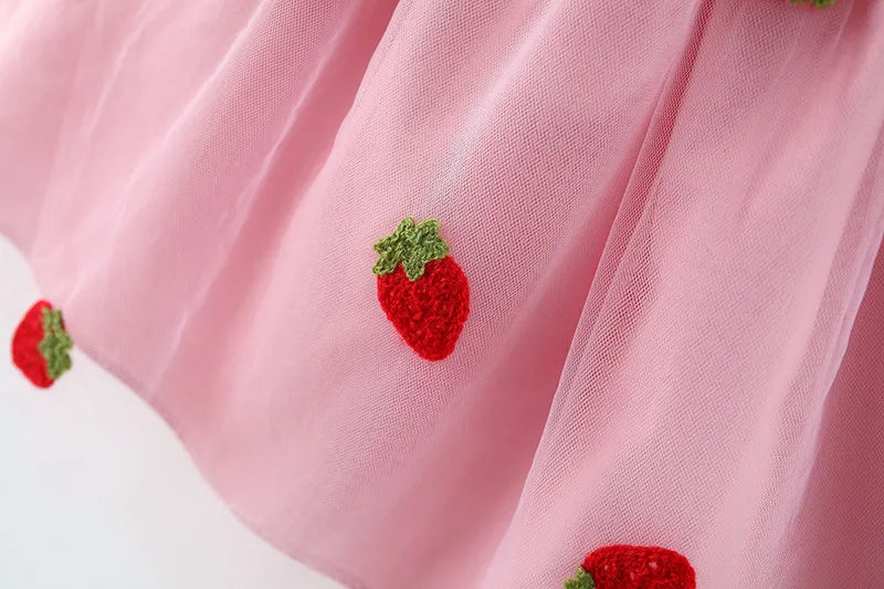 White baby girl's special occasion dress with detailed strawberry embroidery and an elegant bow.