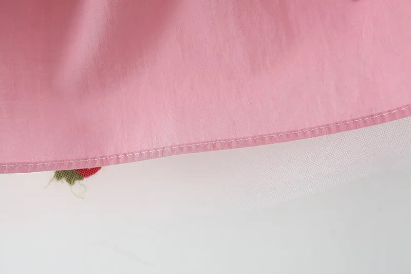 Close-up of the fabric and embroidery on a white girls' summer dress with a subtle bow.