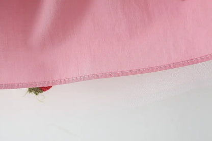 Close-up of the fabric and embroidery on a white girls' summer dress with a subtle bow.