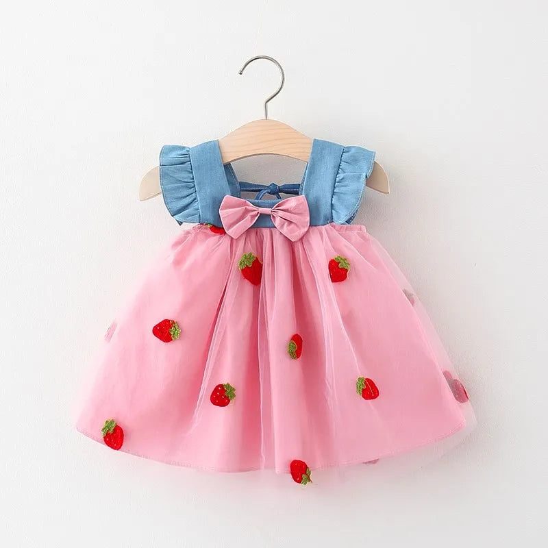 Close-up of a white baby girl's dress featuring intricate strawberry embroidery and a charming bow detail.