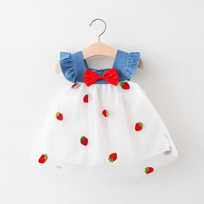 Toddler girl in a cute white strawberry embroidered summer dress with a pretty bow, ideal for parties.