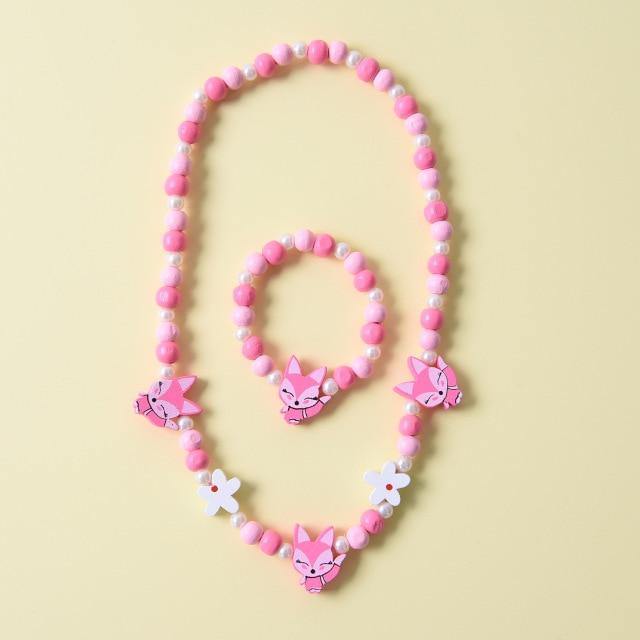Close-up of a girls' wooden animal charm necklace, showcasing unicorn, dolphin, and fox details.