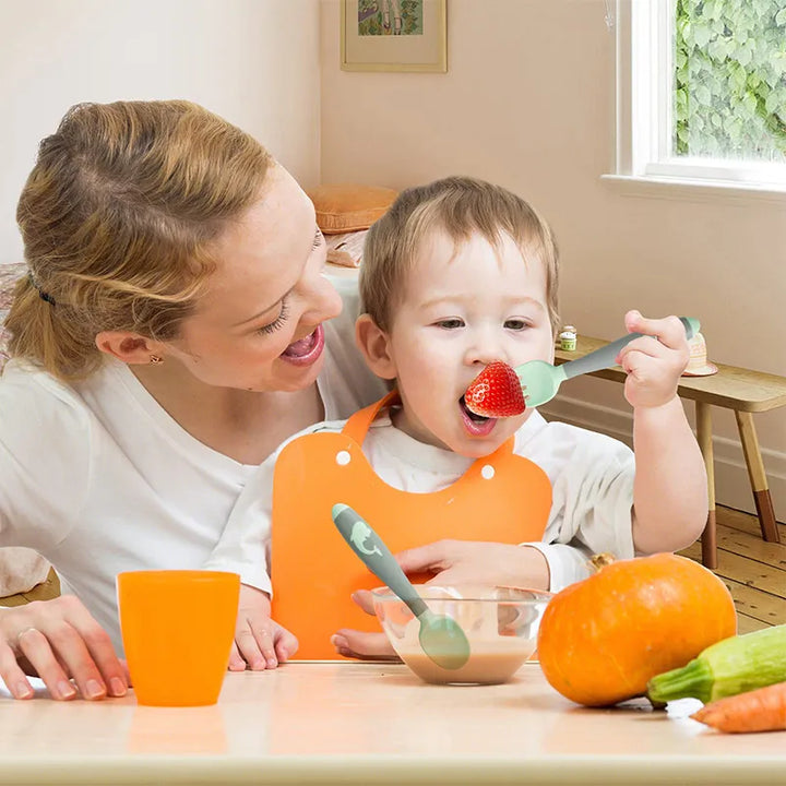 Green silicone training spoon for baby self-feeding. Soft on gums, easy to grip.