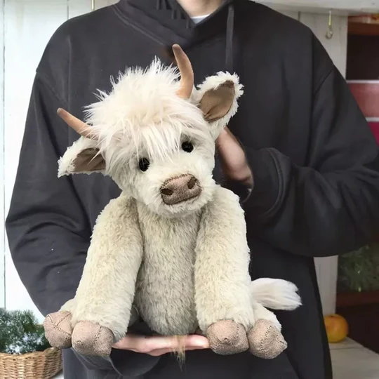 Charming handmade Highland cow plush toy in a sitting pose, showcasing soft alpaca fur; perfect Scottish collectible.