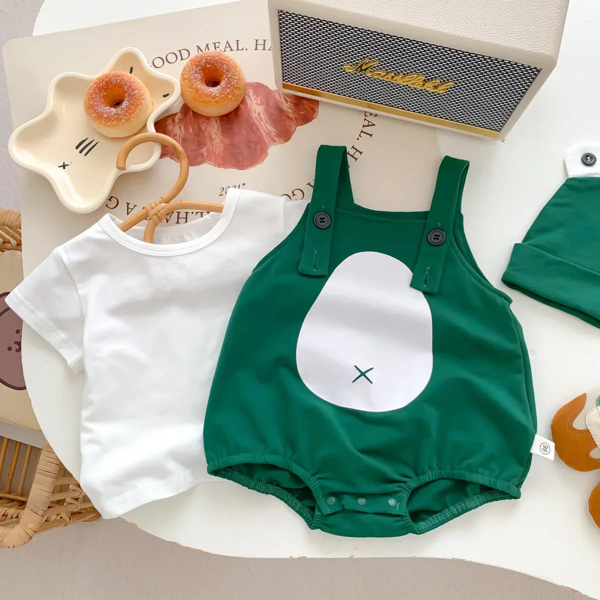 Close-up of soft green frog design on infant cotton romper, featuring snap closures for easy changes.