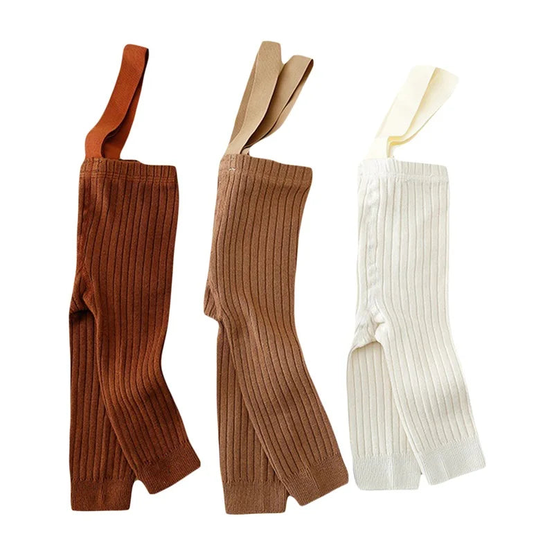 Stack of folded infant girl ribbed knit overalls in various colors, ready for baby clothing collection.