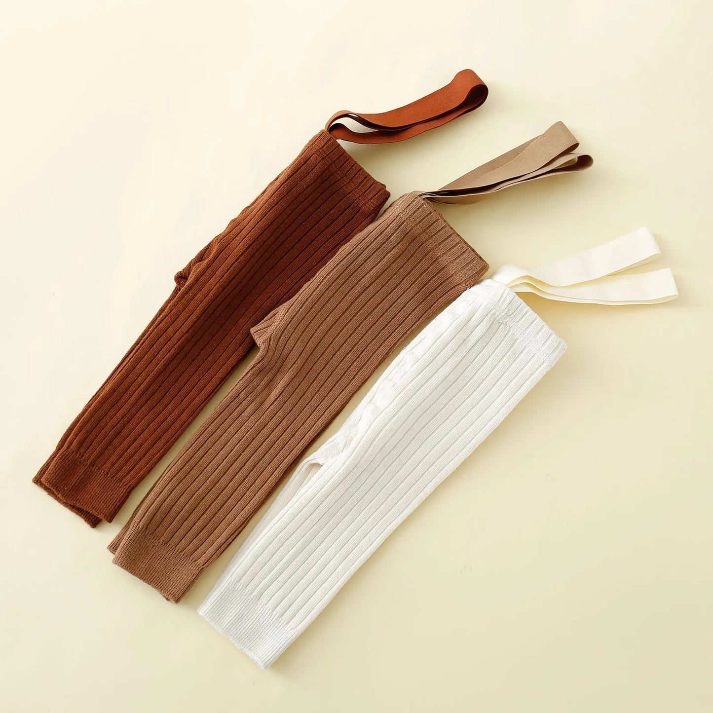 Close-up of ribbed knit fabric on infant girl's overalls, showcasing texture and quality of baby jumpsuit.