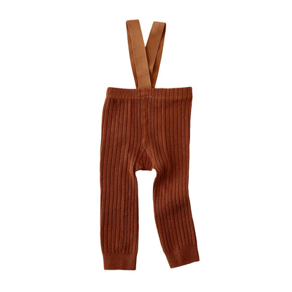 Infant girl modeling ribbed knit overalls, comfortably seated, highlighting the flexibility of the baby clothing.