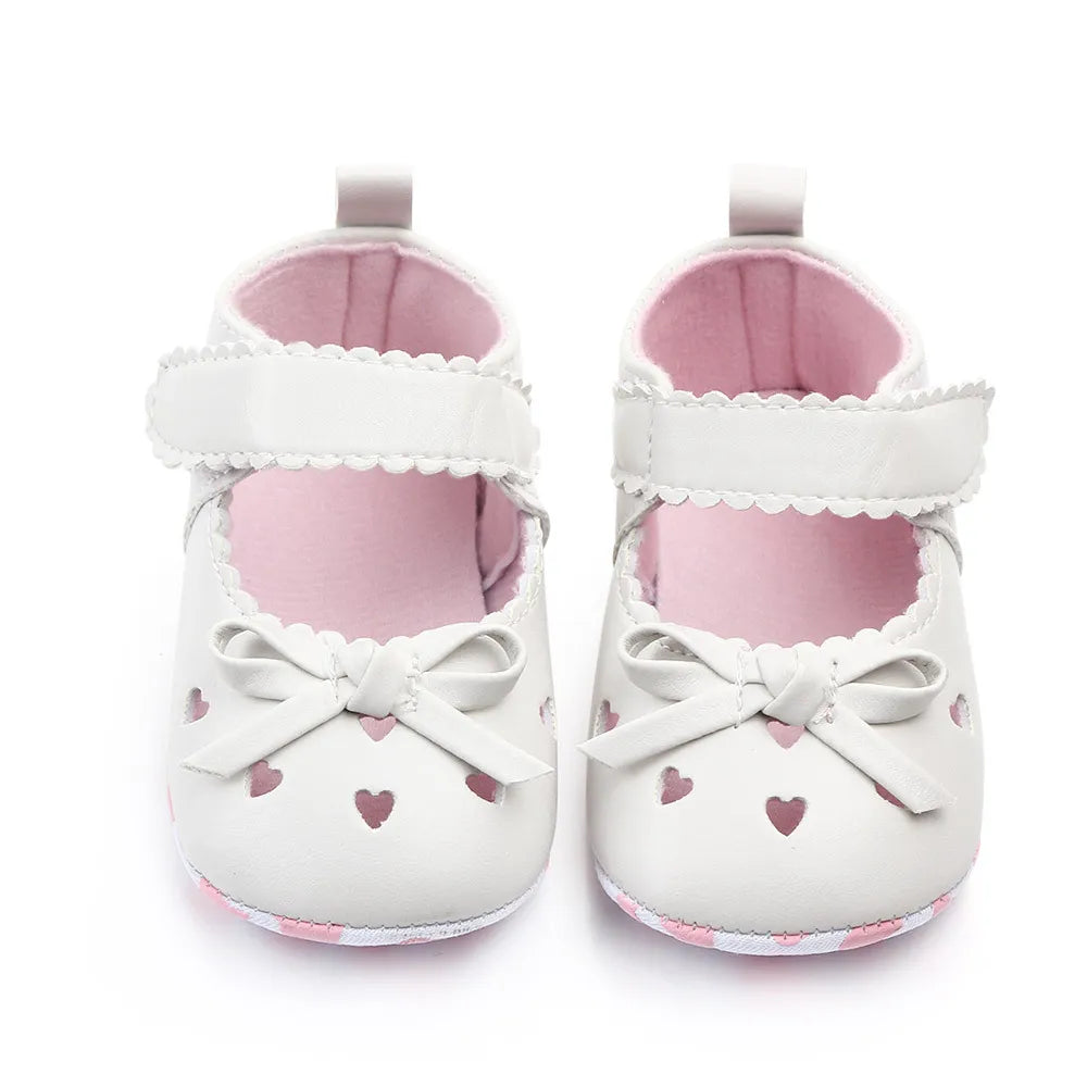 Soft sole baby girl shoes in white with adorable ribbon bows, ideal for first steps