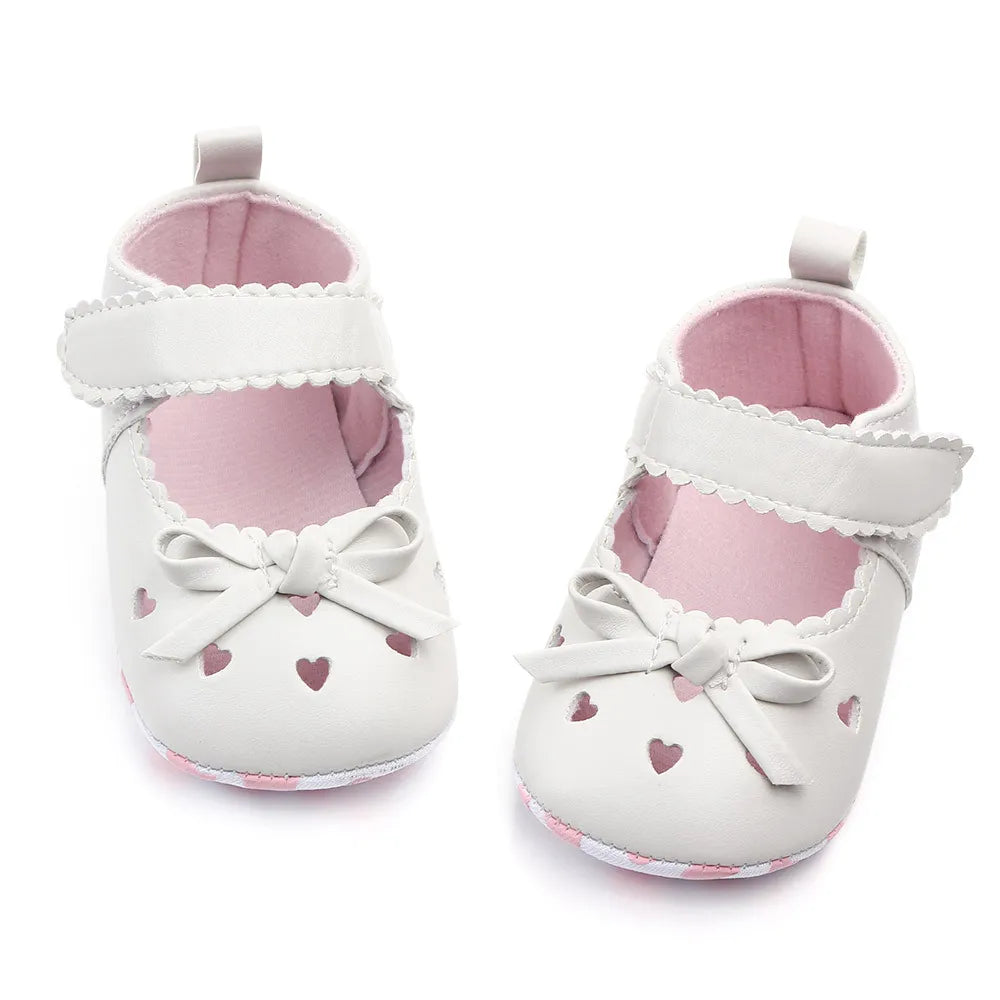 Close-up of a pink infant first walker shoe featuring a delicate bow detail