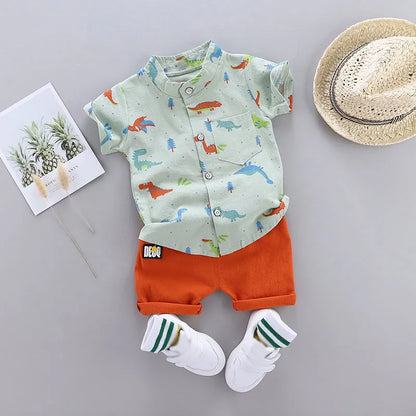 Full view of baby wearing dinosaur print short sleeve top and matching shorts. Comfortable toddler outfit.