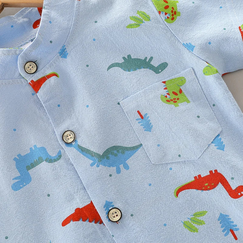 Overhead shot of dinosaur print short sleeve top from infant outfit set. Soft cotton, stand-up collar.