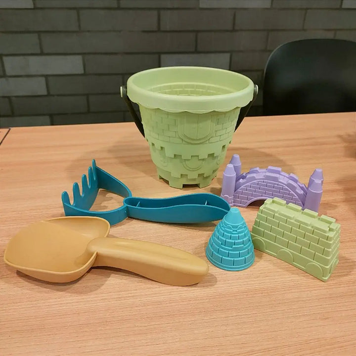 Toddler beach sand toy set featuring blue shovel, green rake, and assorted sandcastle molds