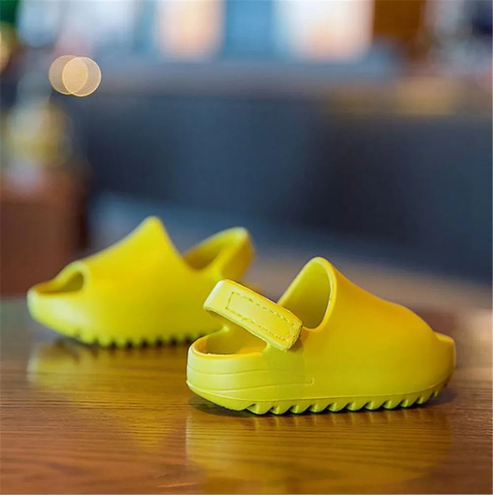 Pair of kids summer sandals in bright green, adjustable velcro, perfect for beach and outdoor play.