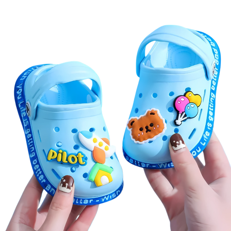 Close-up of a child's foot in a green slip-on clog, showing the back strap and breathable design