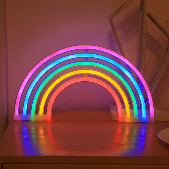 Close-up of a LumiRainbow neon table lamp, casting a soft rainbow glow in a child's bedroom. Home decor.