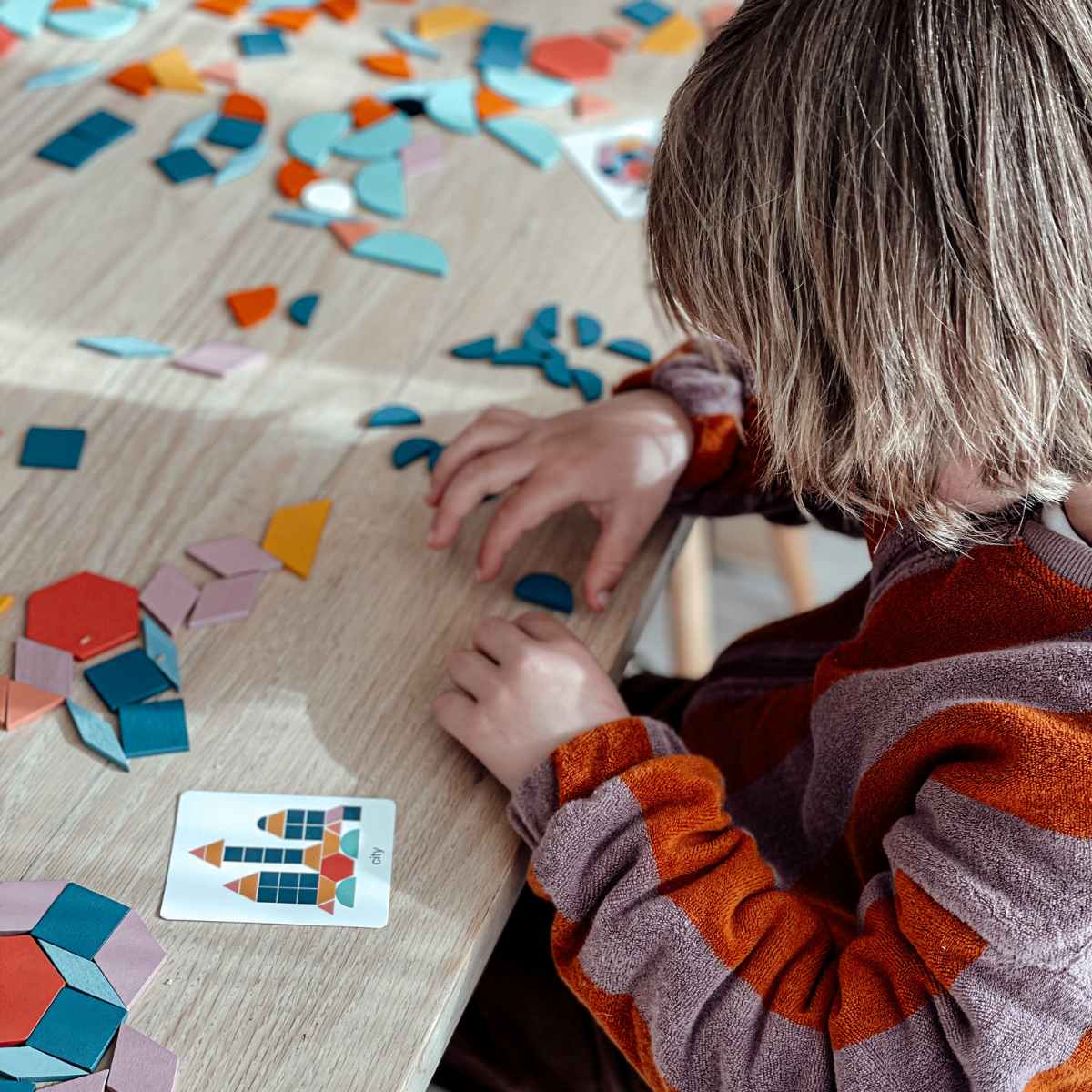 Toddler playing with wooden geometric shape puzzle, a preschool educational toy for sensory development